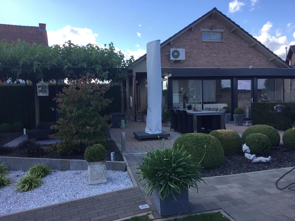 un giardino con una casa con un tavolo e alcuni cespugli di De achtertuin a Maasmechelen