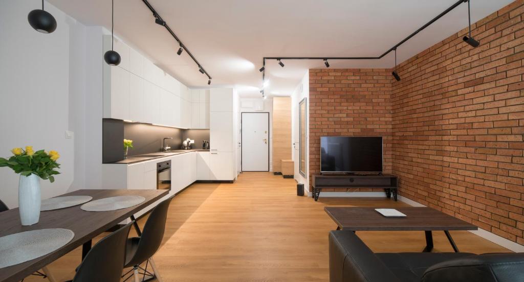a living room with a brick wall and a tv at Villa Wenecja Apartament ALBERO in Poznań