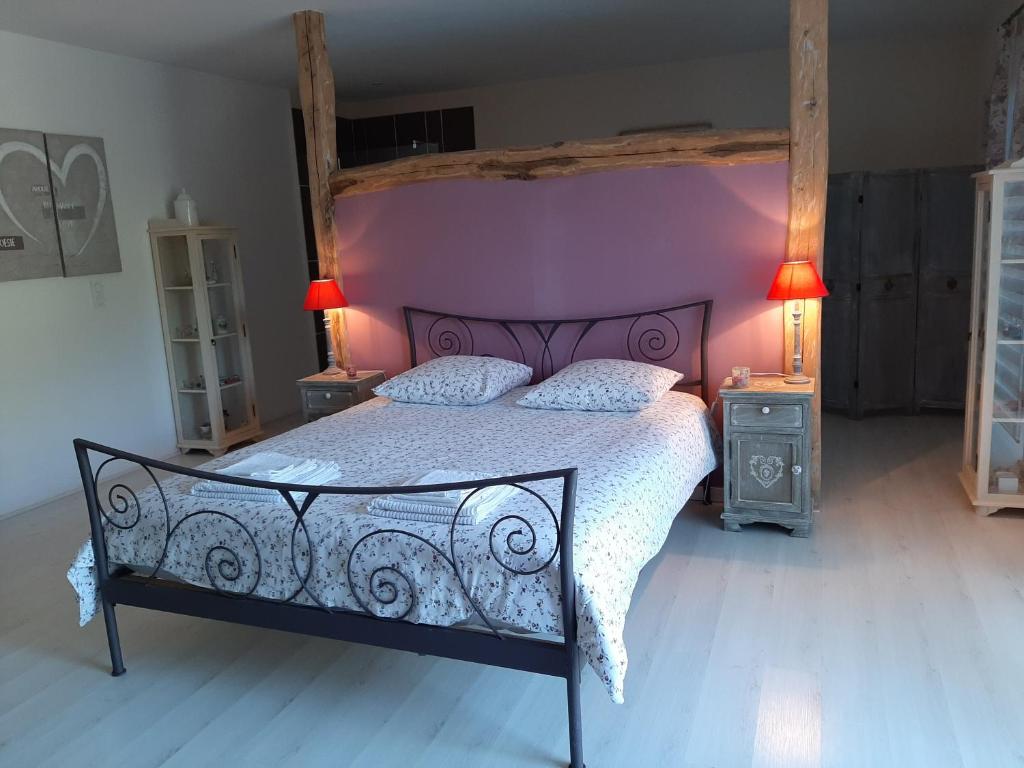 a bedroom with a large bed with a purple wall at Au Cœur de Mauchat in Saint-Martin-de-Fressengeas