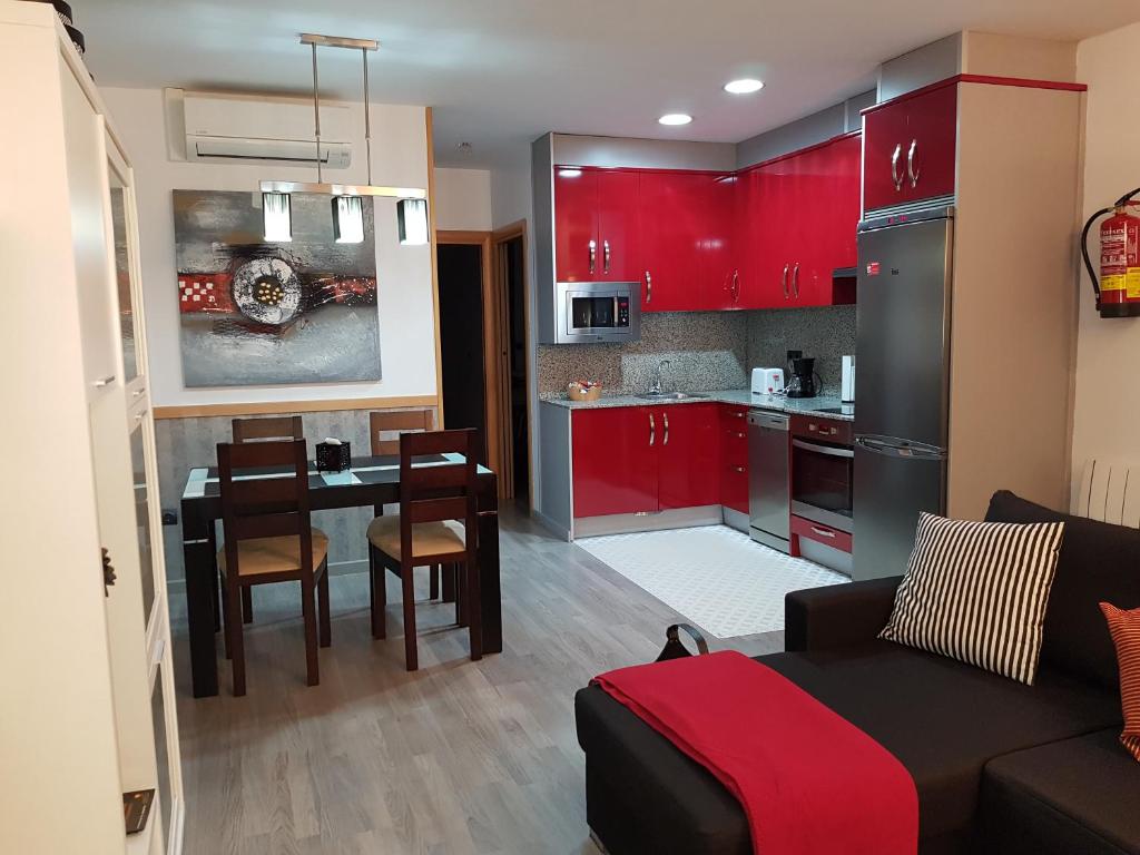 cocina y sala de estar con armarios rojos y mesa en Apartamentos Turísticos "El Jardín" en Teruel