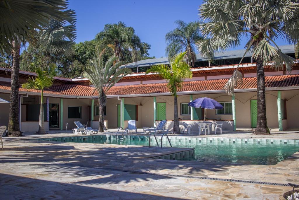 un complejo con piscina y palmeras en RIACHI POUSADA, en Atibaia
