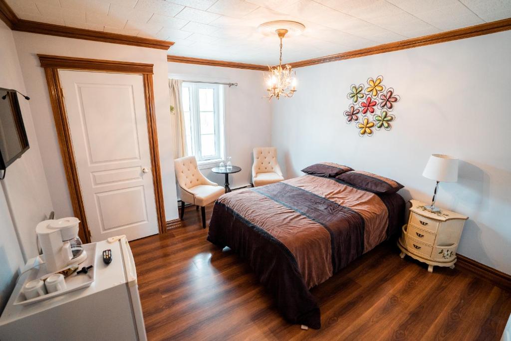 a bedroom with a bed and a table and chairs at Auberge du Vieux Faubourg in Sainte-Anne-des-Monts