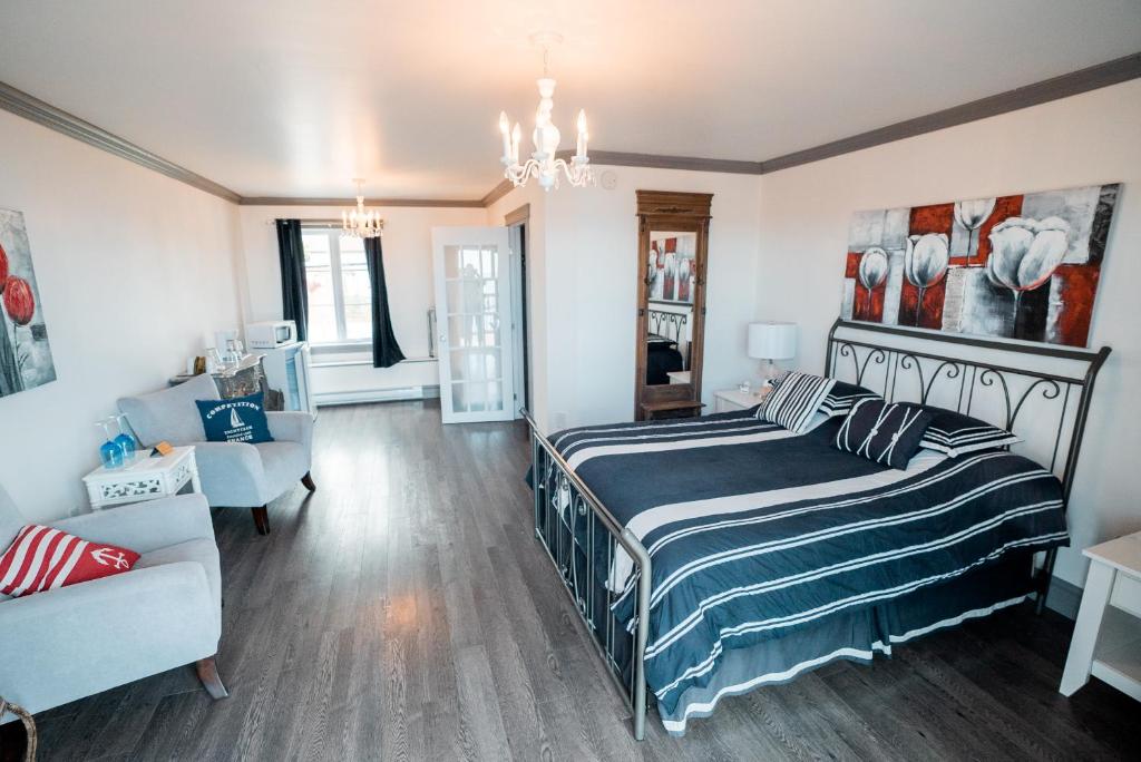 a bedroom with a bed and a living room at Auberge du Vieux Faubourg in Sainte-Anne-des-Monts