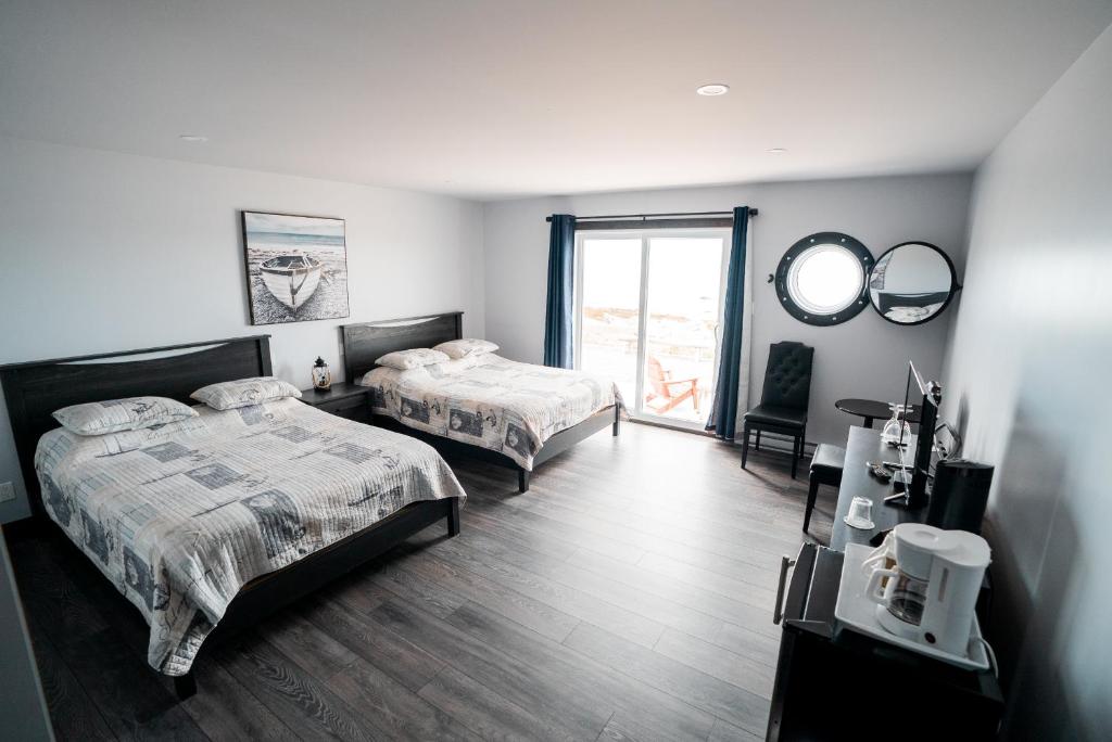 a bedroom with two beds and a mirror at Auberge du Vieux Faubourg in Sainte-Anne-des-Monts