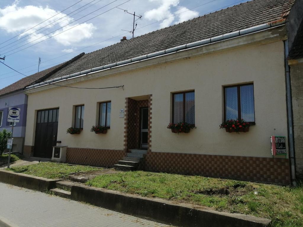 Biały dom z kwiatami na oknach w obiekcie U Ladi w mieście Bulhary
