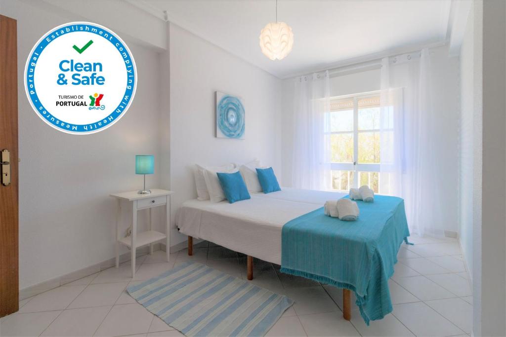 een witte slaapkamer met een bed en een blauwe tafel bij Adalena Oura By ALzira in Albufeira