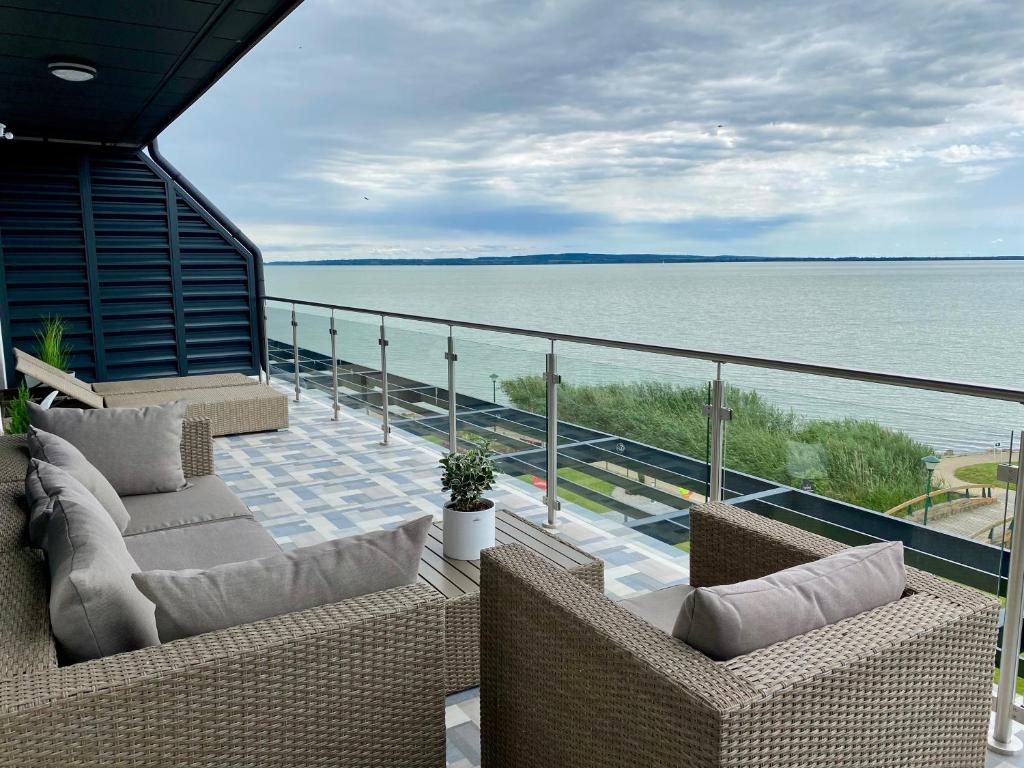 balcón con sofás y vistas al agua en Royal Blue - luxurious flat with 5-star view over Lake Balaton, en Keszthely