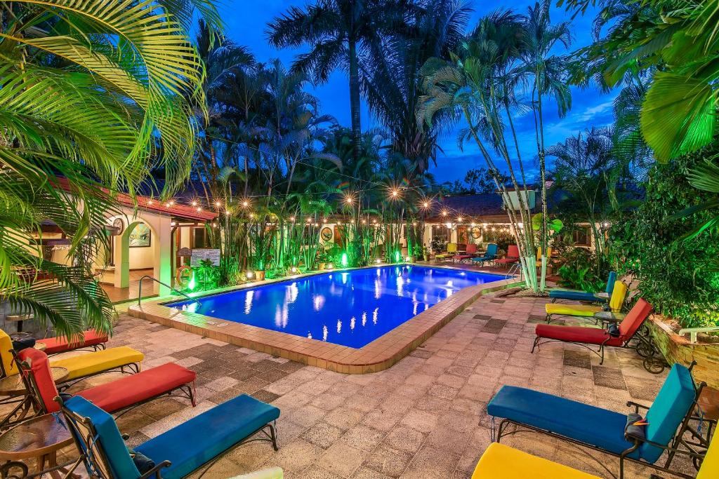 a resort pool with chairs and palm trees at night at Hotel Villas Lirio in Manuel Antonio