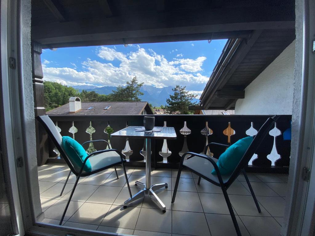 een patio met een tafel en stoelen op een balkon bij Ferienhaus Alpenjuwel in Garmisch-Partenkirchen