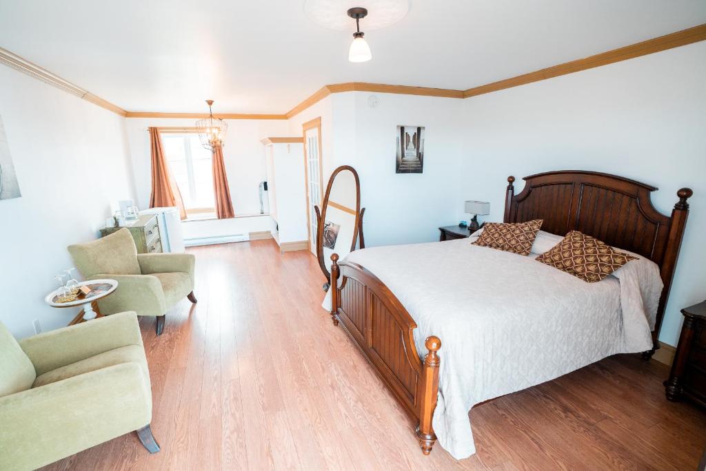 a bedroom with a bed and a couch and a chair at Auberge du Vieux Faubourg in Sainte-Anne-des-Monts