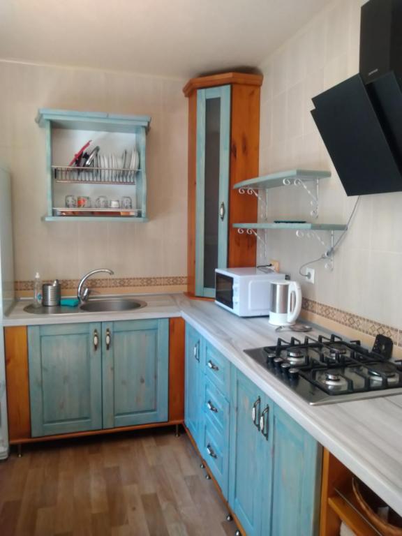 a kitchen with blue cabinets and a stove top oven at Апарт готель,, Червона Рута,, in Skhidnitsa