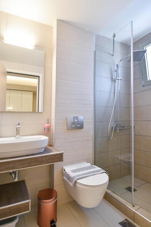 a bathroom with a toilet and a sink and a shower at On Board Luxury Studios in Sarti