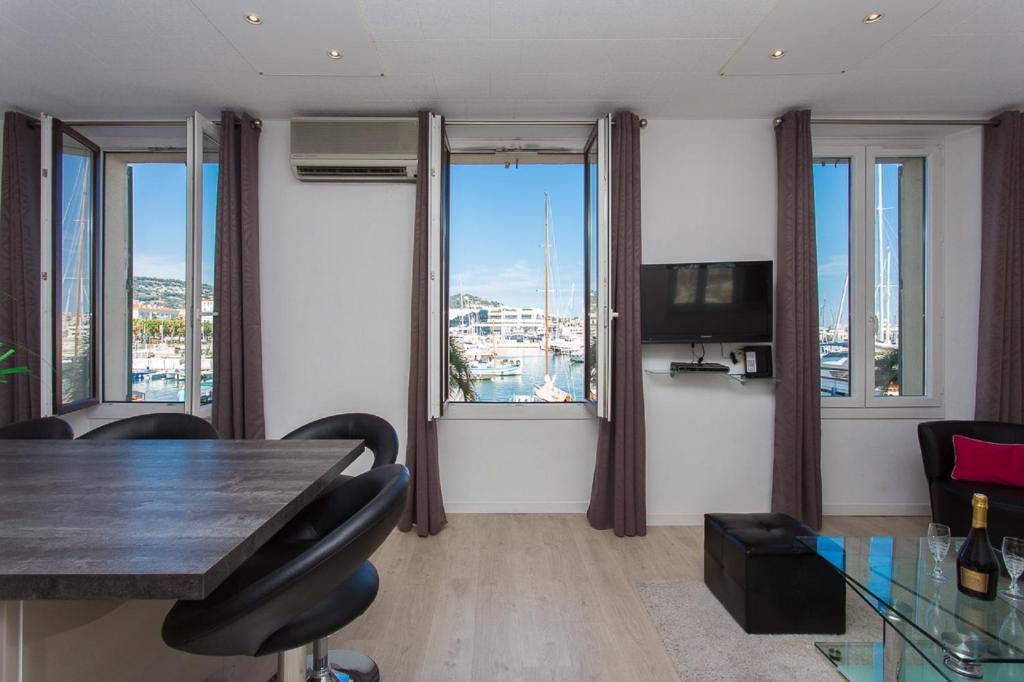 un soggiorno con tavolo, sedie e finestre di COTE PORT a Cannes
