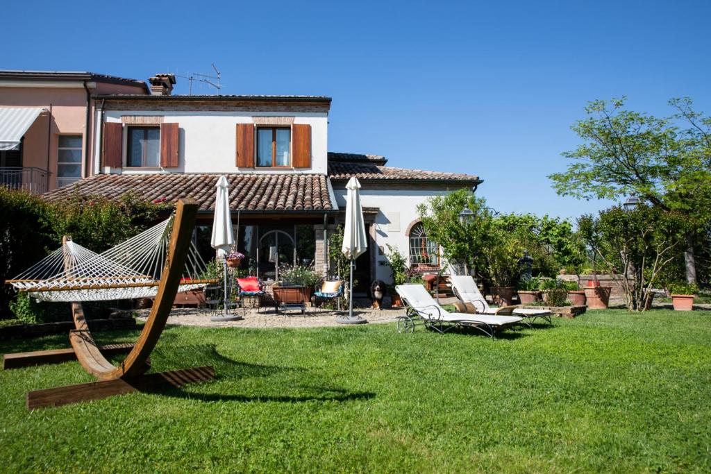 un patio con una hamaca y sillas y una casa en Cascina Vecchia Bellaria B&B en Bellaria-Igea Marina