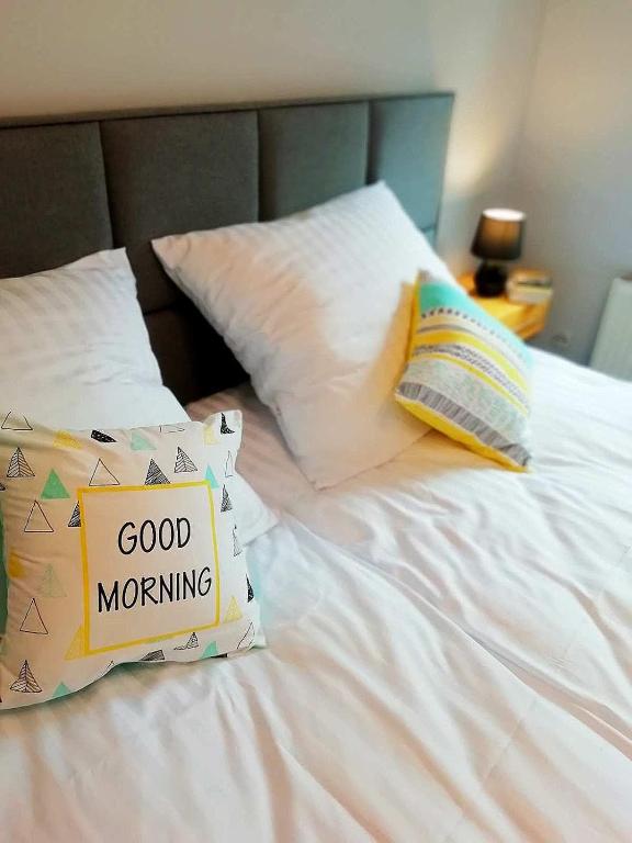 a white bed with a good morning sign on it at Apartament Fabryka Endorfin Kłodzko in Kłodzko