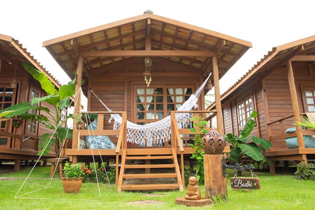 a wooden house with a hammock in front of it at Pousada Villa del Lótus in Itarema