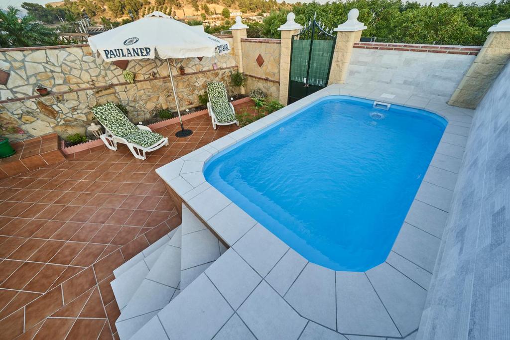a swimming pool with two chairs and an umbrella at Casa Rural Mi Cortijo in Nerja