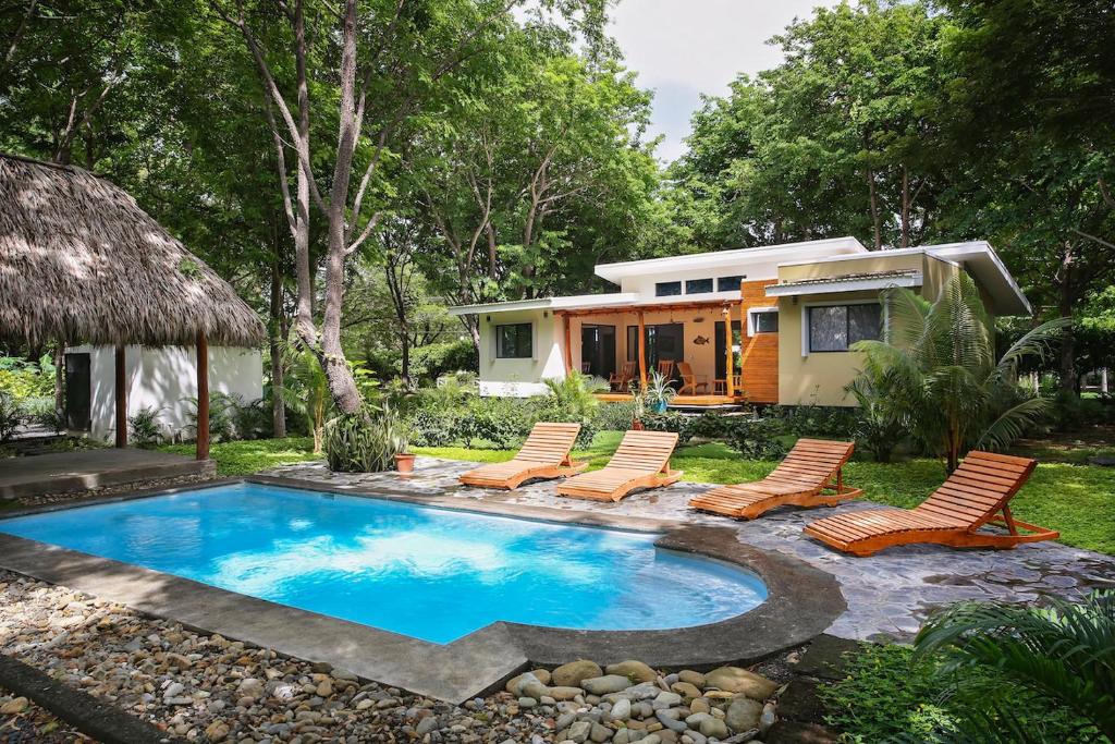 a tiny house with a swimming pool and chairs at Eco Casita Phase III #2: Casa de Olas in Rivas