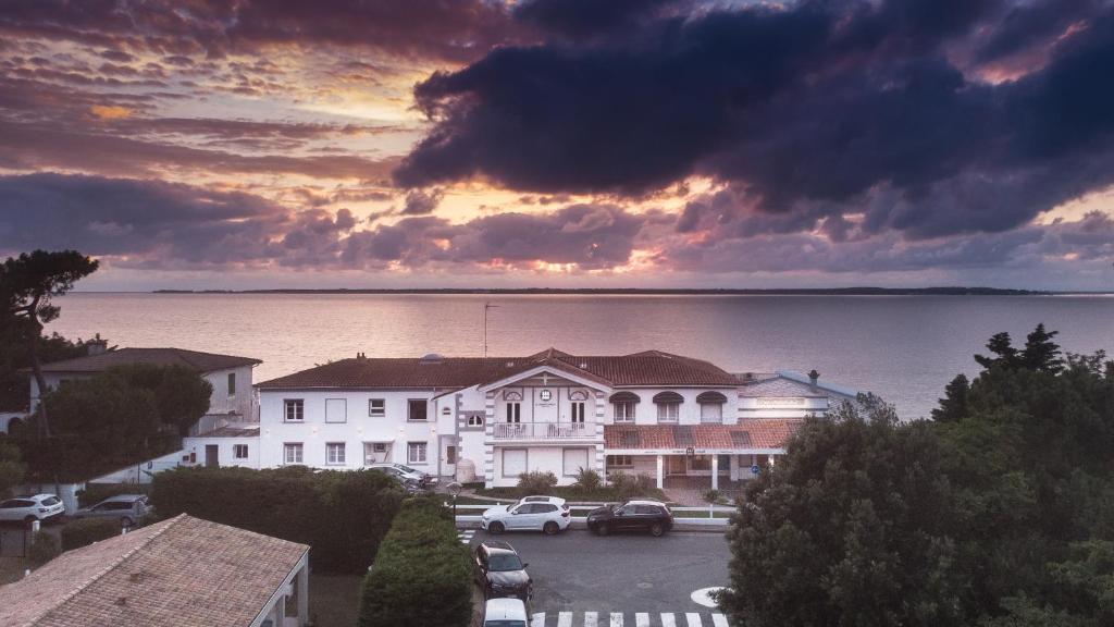 ein Gebäude mit einem Parkplatz vor dem Wasser in der Unterkunft Beach Hotel - Le Grand Chalet in Ronce-les-Bains