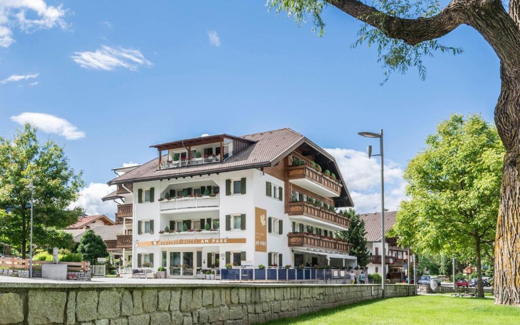 un edificio blanco con balcones y un árbol en Boutique Hotel Am Park, en Valdaora