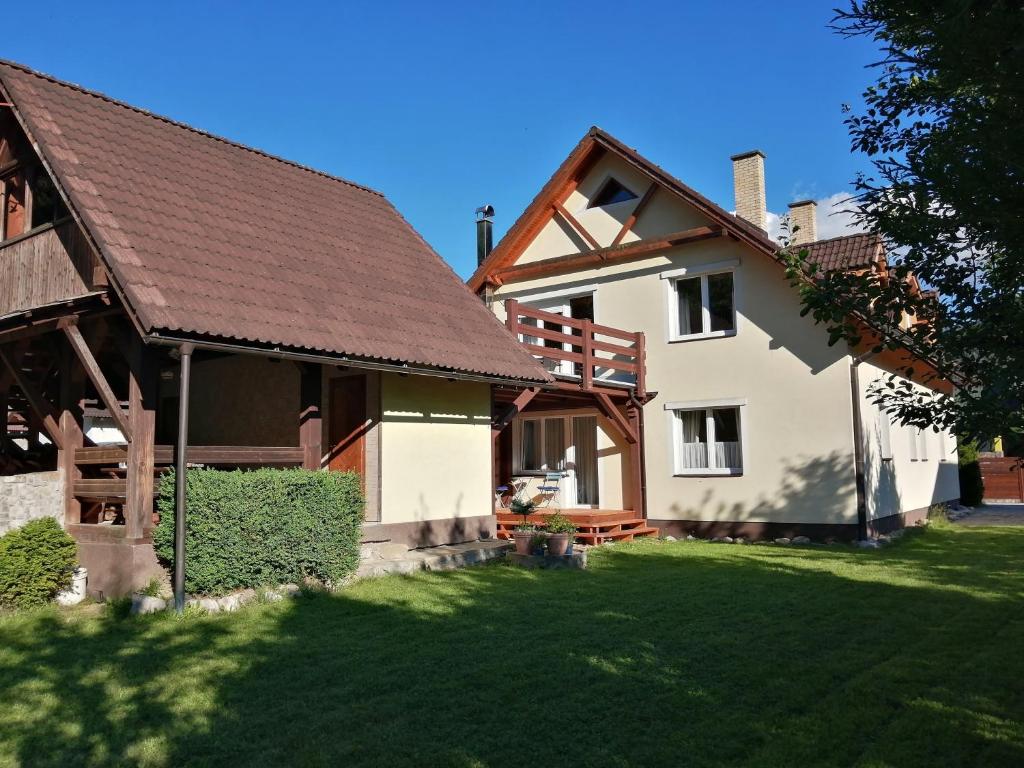 a white house with a brown roof and a yard at Apartmány Skalka in Terchová