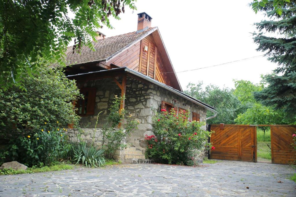 a stone house with a wooden gate and a driveway at Tanya Üdülőház in Garáb