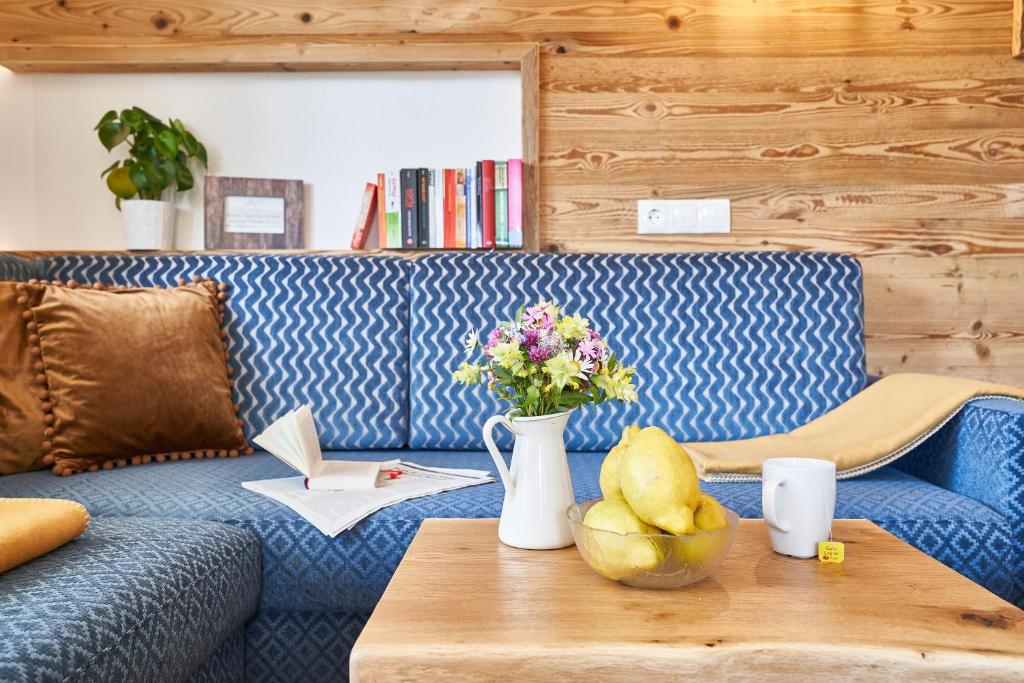un divano blu con un vaso di fiori su un tavolo di Das Habitat a Leutasch