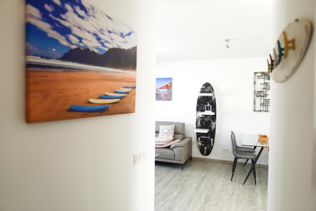 - un salon avec un canapé et une planche de surf sur le mur dans l'établissement Apartment Cucharas Beach - Piscina - Beach 2 min. - AC - Wifi, à Costa Teguise