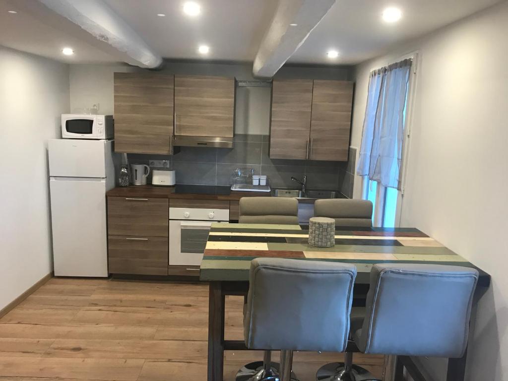 a kitchen with a table and chairs and a refrigerator at Appartement lac et montagne in Saint-André-les-Alpes