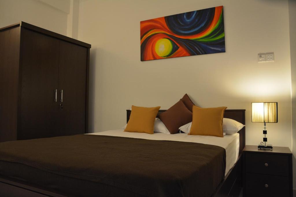 een slaapkamer met een bed met een schilderij aan de muur bij Panoramic Holiday Apartment - Luxury Studio | Nuwara Eliya in Nuwara Eliya
