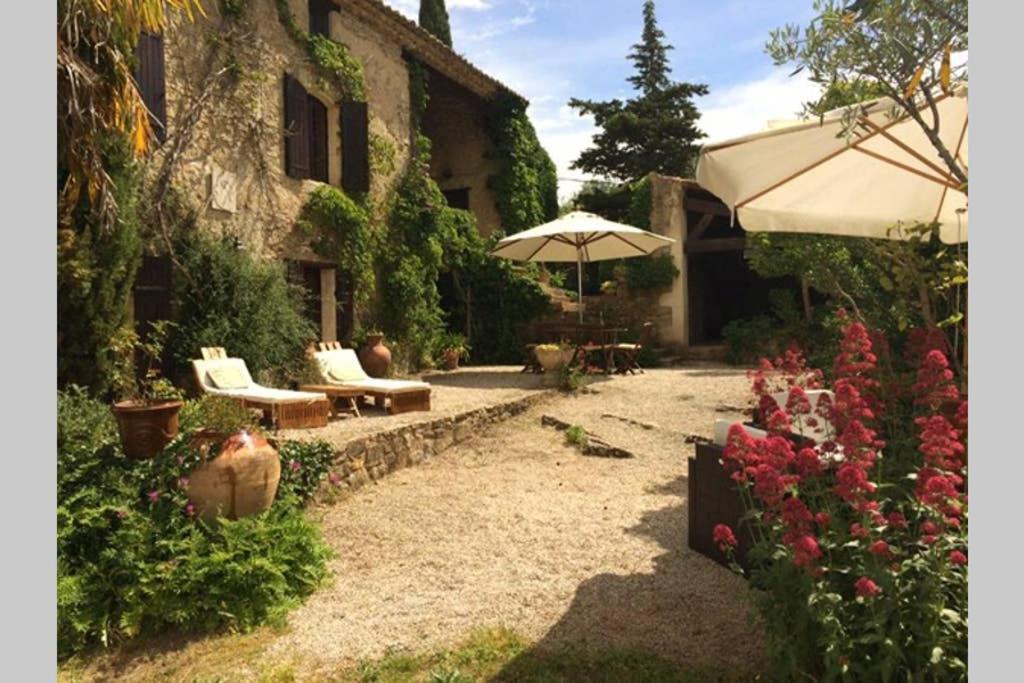 un giardino con sedie e ombrellone di fronte a una casa di Secluded South of France stone mas built 1833 4 bedroom a Saint-André-dʼOlérargues