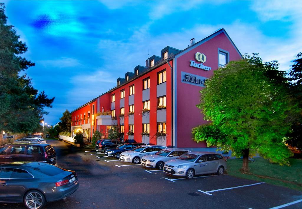 a building with cars parked in a parking lot at Hotel Kübler in Wendelstein