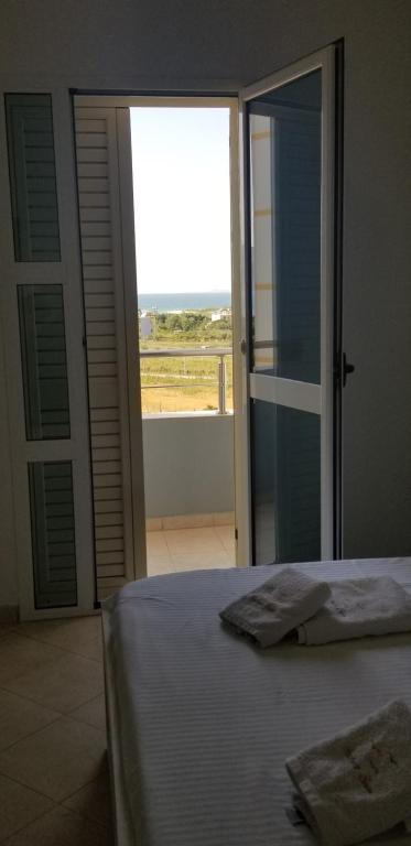 a bedroom with a bed and a sliding glass door at Apartments Rezidenca Sinani Orikum in Orikum