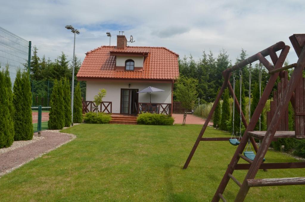 uma casa com um quintal com um baloiço em Domek nad jeziorem em Dabrówno