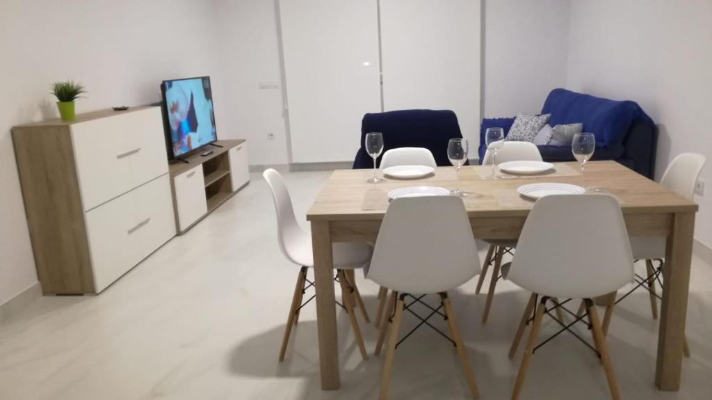 jadalnia z drewnianym stołem i białymi krzesłami w obiekcie Apartamento “El Lometico” w mieście Carboneras