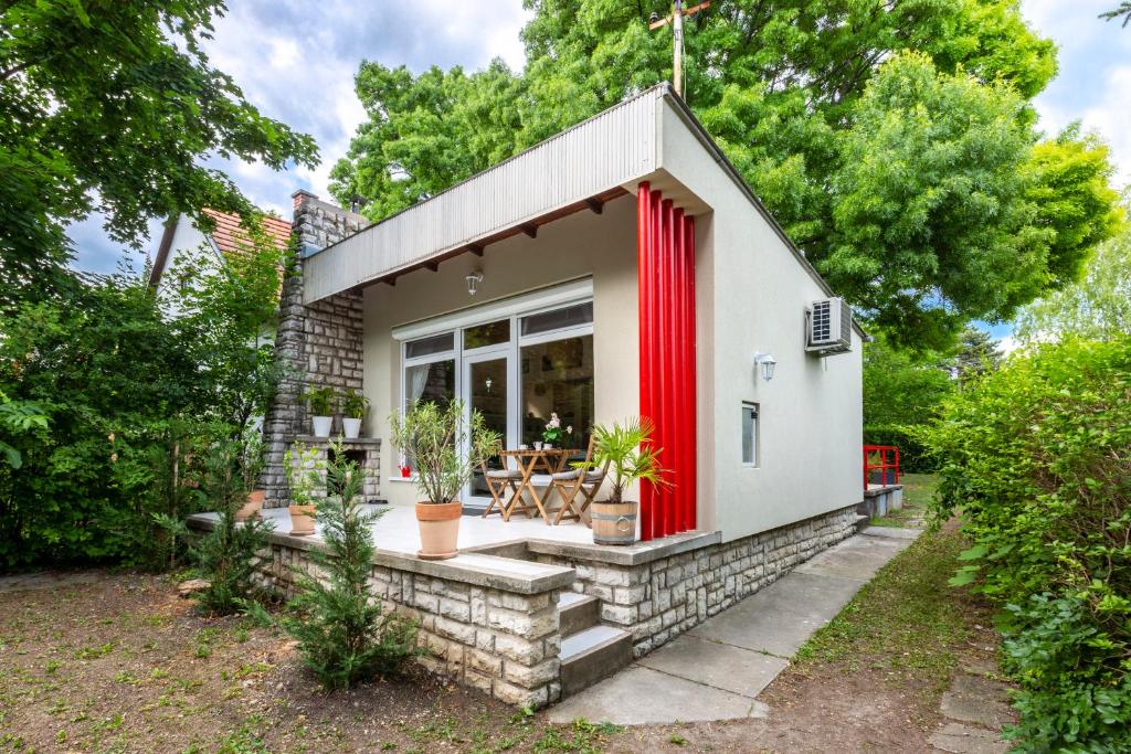 a tiny house with red curtains and a patio at Cottage by the Lake in Balatonudvari