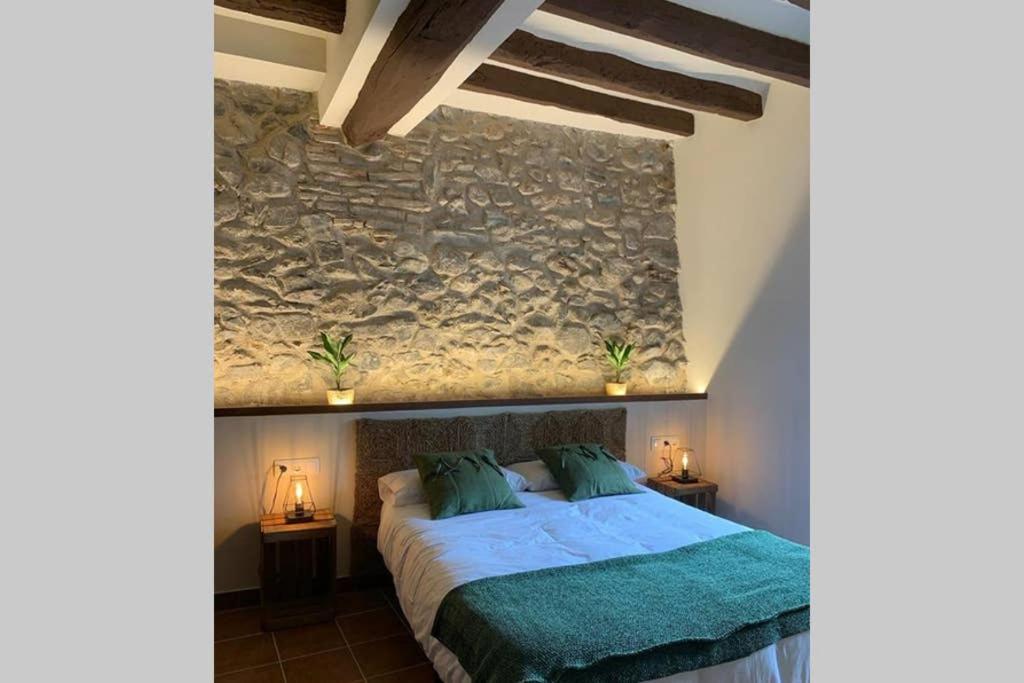 - une chambre avec un lit et un mur en pierre dans l'établissement Ca l'Arcadi, à Alforja