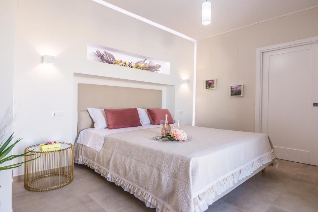 a white bedroom with a large bed with red pillows at HYPNOTIC GUESTHOUSE in Budoni