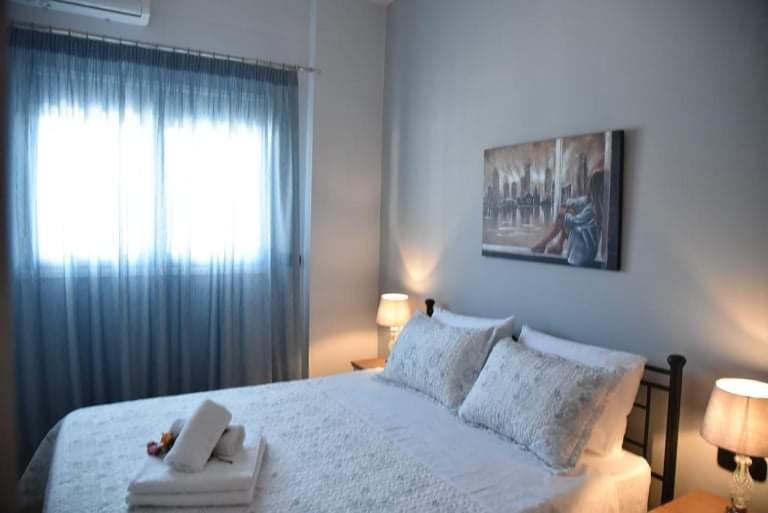 a bedroom with a large white bed with a window at Family Apartments 4 in Lékhaion