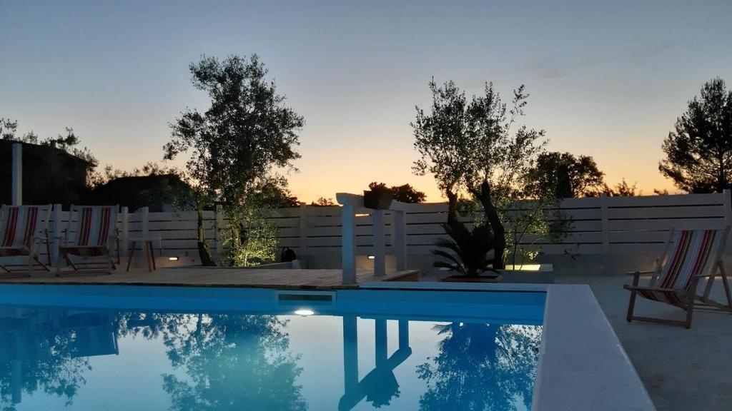 une piscine dans une arrière-cour avec une clôture blanche et des arbres dans l'établissement Villa Nina, à Biograd na Moru