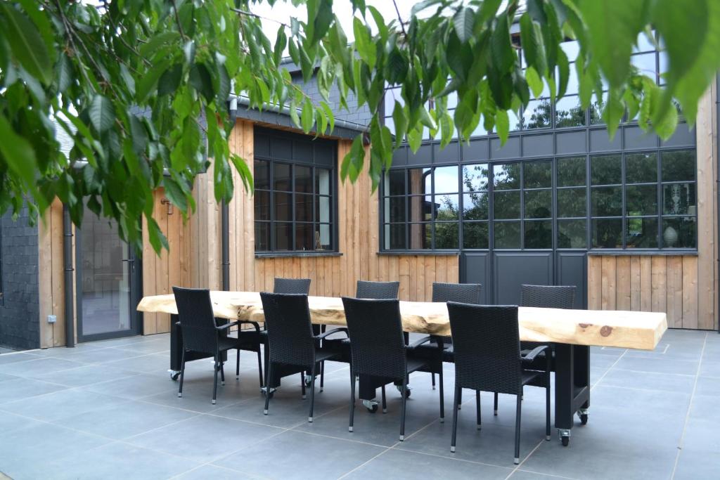 a wooden table and chairs in front of a building at Maison du chien vert in Corbion