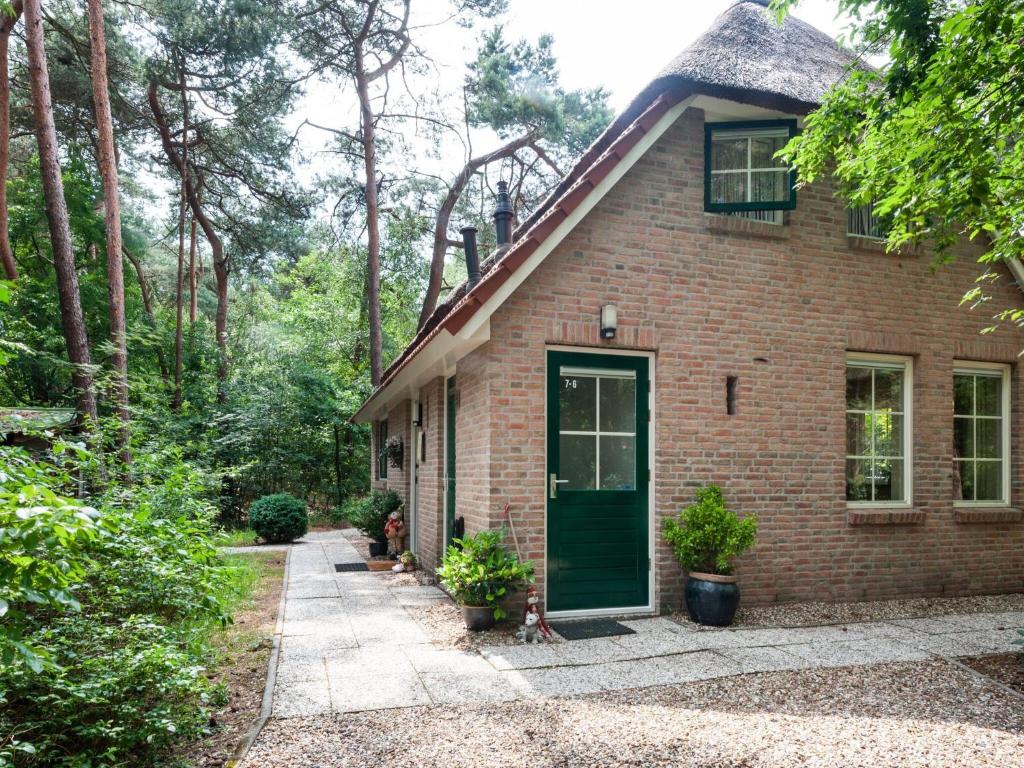 a brick house with a green door and trees at Holiday Home in Beerze Overijssel with Lush Garden in Beerze