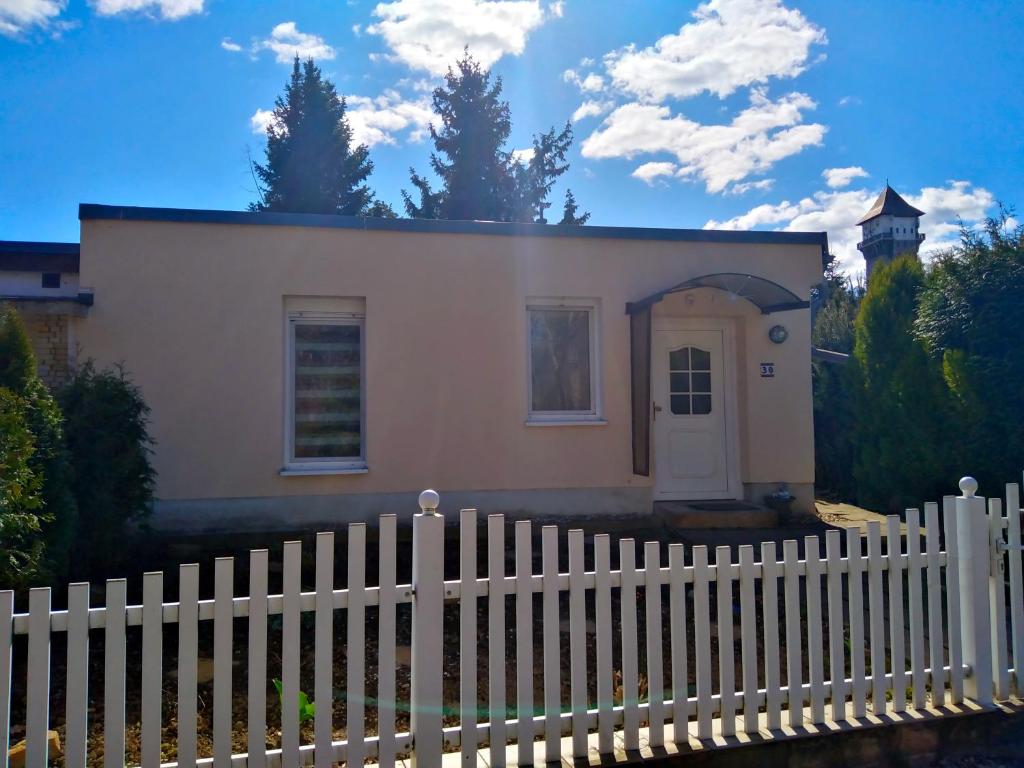 a small white house behind a white fence at Ferienhaus am Ellerbach in Bad Dürrenberg