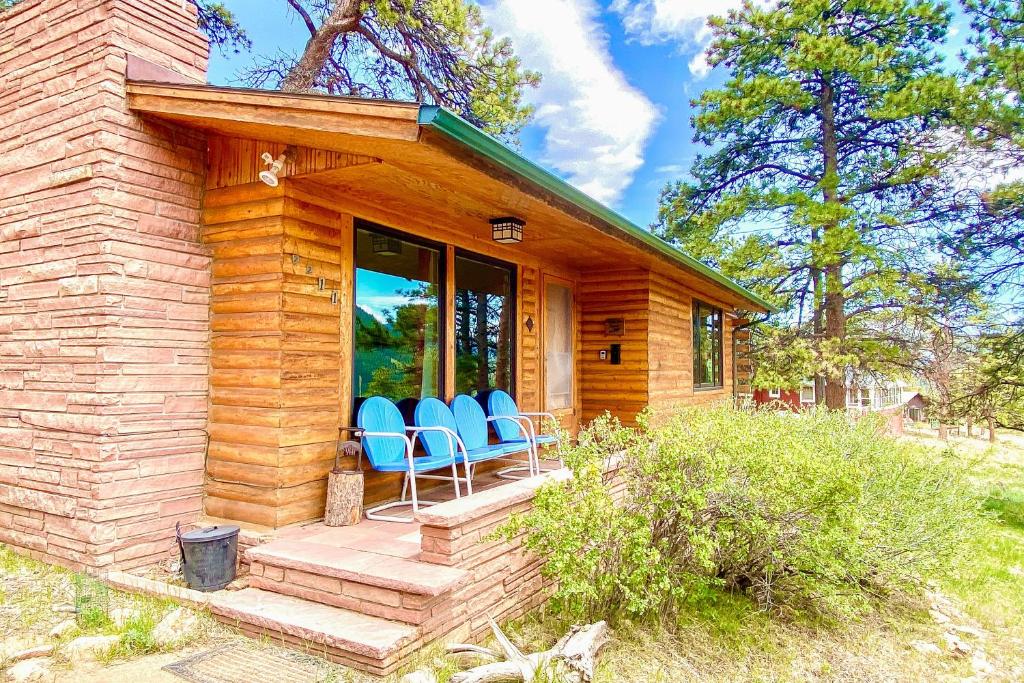 Cabaña de madera con sillas azules en el porche en Rocky Mountain High en Estes Park
