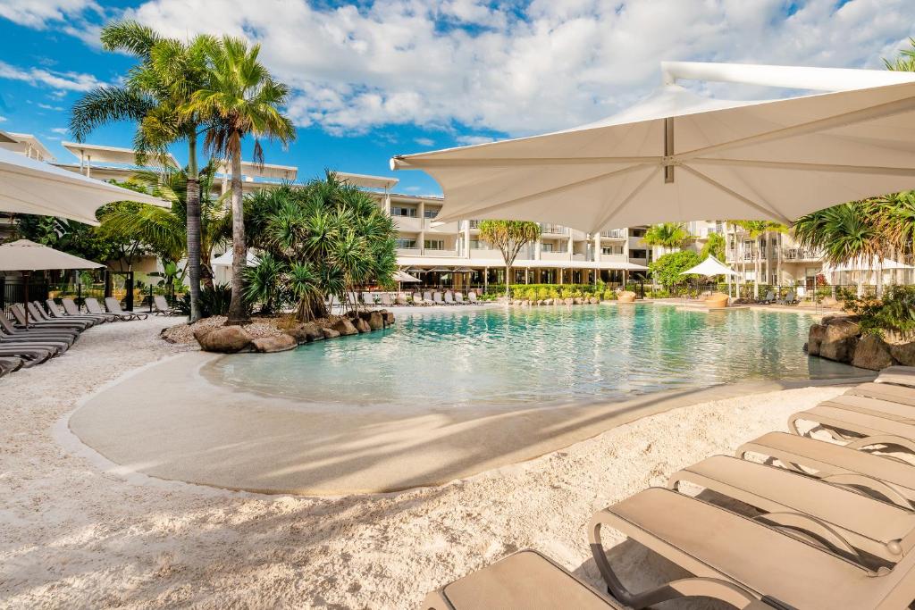 a resort swimming pool with chairs and an umbrella at Peppers Salt Resort & Spa in Kingscliff