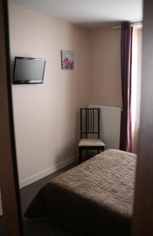 a small bedroom with a bed and a chair at Hôtel du Roussillon in Paris