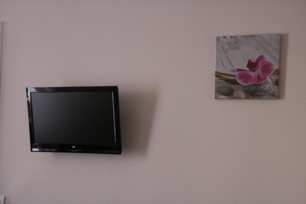 a flat screen tv hanging on a wall at Hôtel du Roussillon in Paris