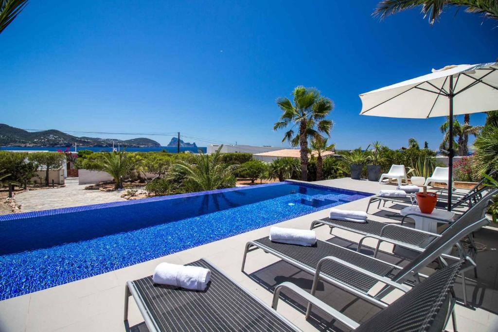 una piscina con sedie e ombrellone accanto a una piscina di Villa Arola a Cala Comte