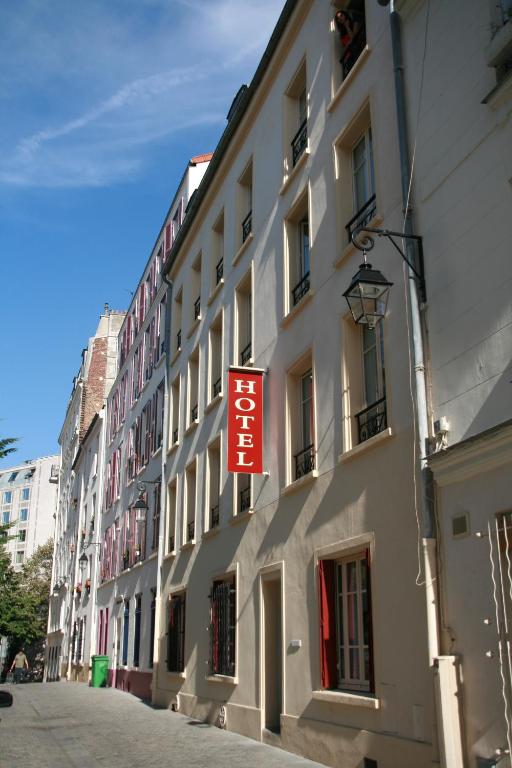 a building with a red sign on the side of it at Hôtel du Roussillon in Paris