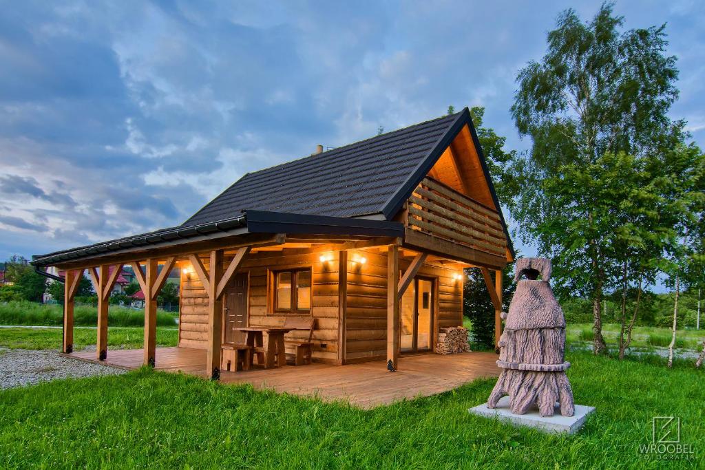 uma cabana de madeira com um deque e uma estátua em Domek Przy Stoku em Tylicz